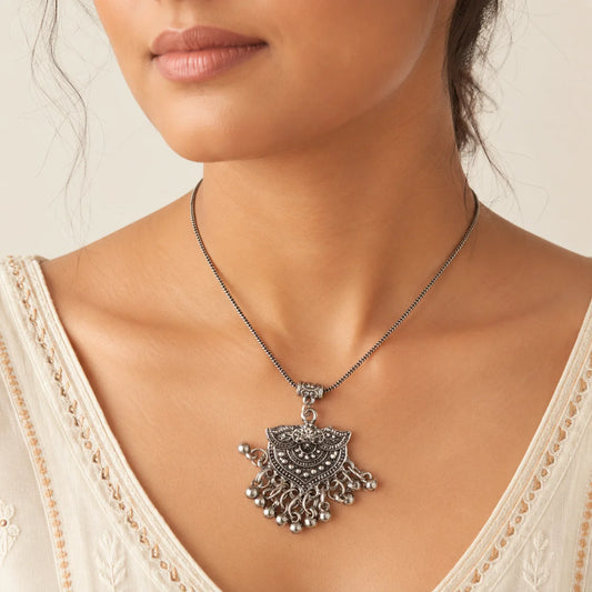 "Oxidised silver-tone necklace
and earrings set featuring an intricate statement pendant with ghungroo-style danglers and matching ethnic stud earrings."
