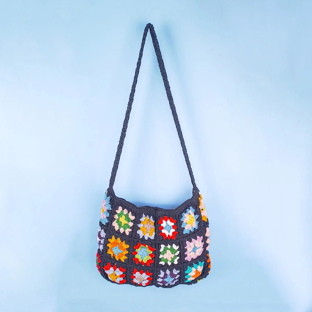 Black crochet granny square bag with multicolor patchwork design, handcrafted boho style shoulder bag with vibrant squares and textured knit pattern.