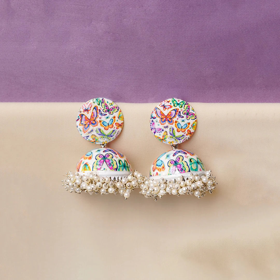 Multicolor butterfly print dome jhumka earrings with pearl cluster fringe detailing. White base with vibrant butterfly motifs in pink, blue, and yellow tones. Lightweight statement earrings perfect for festive and ethnic wear styling.