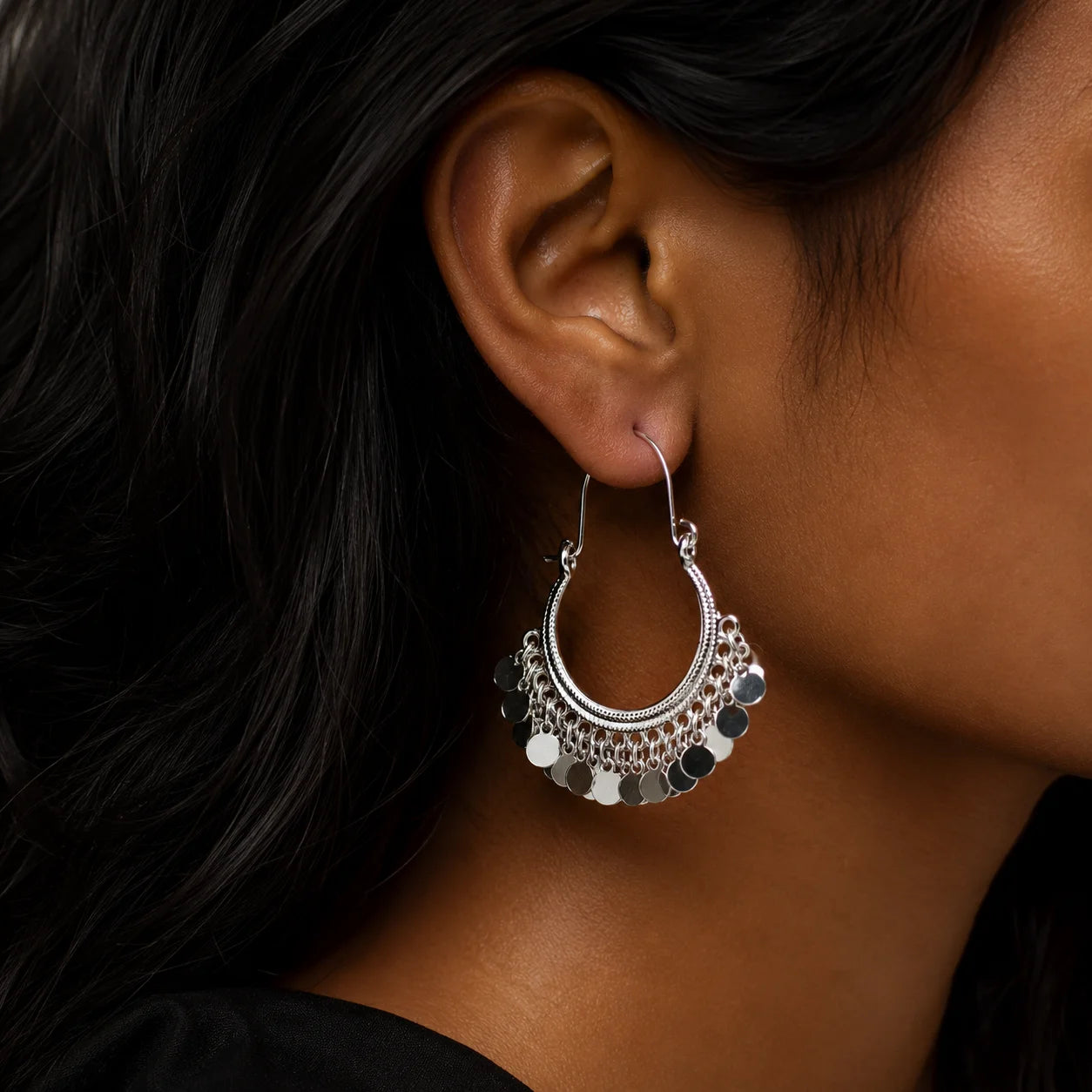 Silver plated coin hoop earrings with dangling disc charms on wooden surface. Lightweight bali hoop earrings with silver coin drops for daily ethnic fusion wear.
