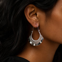 Silver plated coin hoop earrings with dangling disc charms on wooden surface. Lightweight bali hoop earrings with silver coin drops for daily ethnic fusion wear.