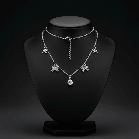 Bold silver tone necklace with large crystal bow charms and round crystal accent. Stainless steel with adjustable extender for fit. A statement demi-fine necklace for western, fusion, or party outfits.