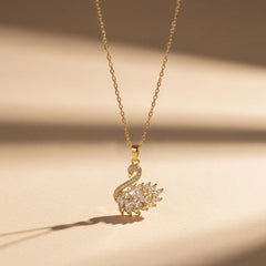 A gold swan pendant with clear cubic zirconia stones on an 18K gold plated chain. Other options include an 18K gold swan necklace with crystal detailing, a minimalist swan demi-fine necklace, and a graceful gold swan pendant for women.