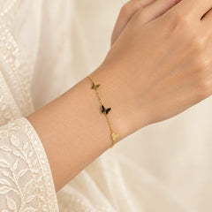 "Gold-tone delicate chain
bracelet featuring three butterfly charms, including a central dark enamel butterfly, with an adjustable extension chain."