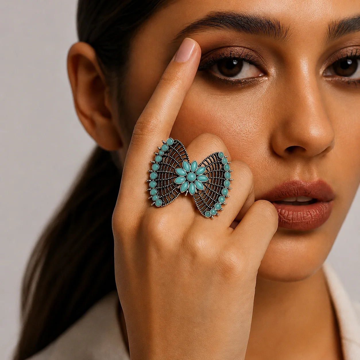 "Oxidised silver-tone
statement ring featuring an intricate butterfly-inspired design with turquoise accents and a floral centre."