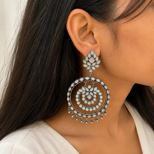 "Oxidised silver-tone statement
earrings with floral white stone detailing, layered circular design, and ghungroo drops. Traditional ethnic dangler earrings for women, perfect for weddings, festive celebrations, Navratri, Diwali, cultural events, and Indo-western styling."