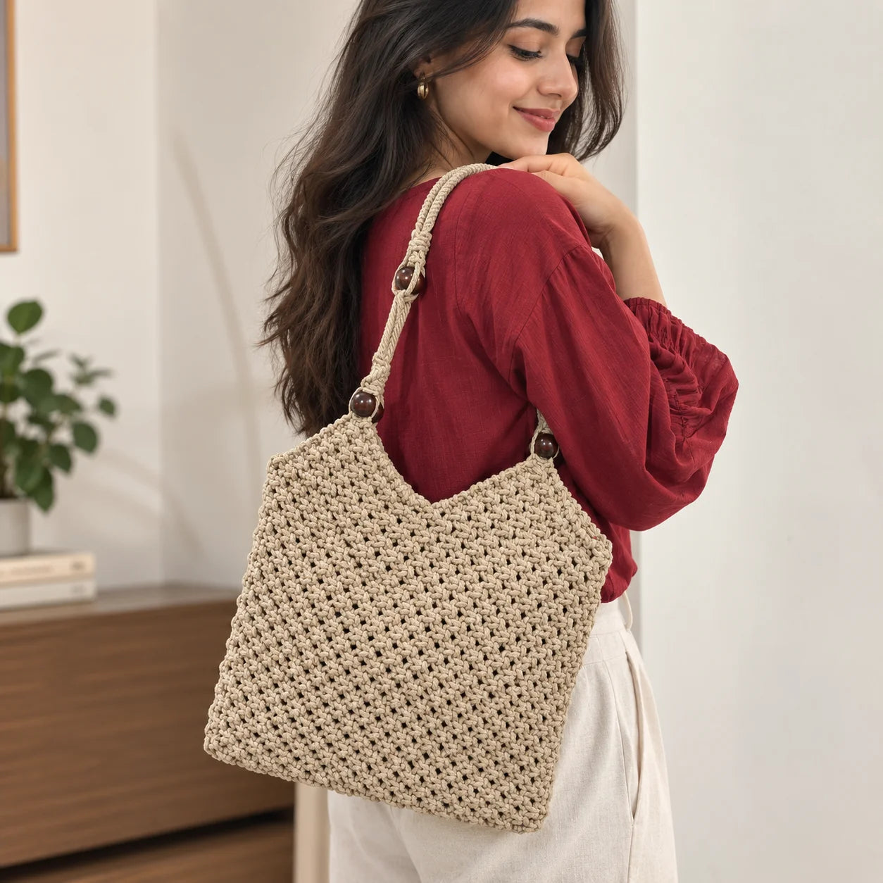 "Beige macramé crochet
shoulder bag with a textured woven pattern, long braided straps, and dark wooden bead accents."