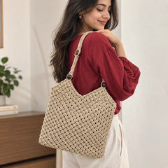 "Beige macramé crochet
shoulder bag with a textured woven pattern, long braided straps, and dark wooden bead accents."