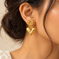 Gold double heart drop earrings featuring two sculpted heart shapes with a glossy polished finish.