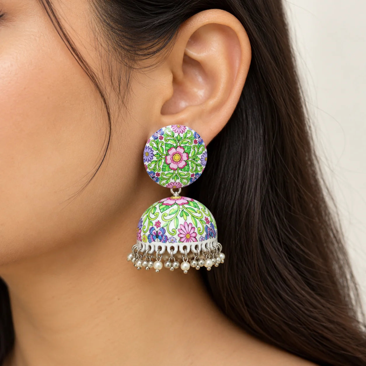 Multicolour floral Meenakari jhumka earrings with round printed tops, dome-shaped drops, silver-tone detailing, and dangling pearl charms.
