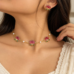 Gold-tone lotus choker necklace and matching earrings featuring red lotus motifs, green enamel accents, and pearl details.