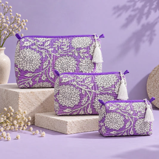 Purple quilted fabric pouch featuring white floral prints, a matching purple border, and a white tassel.