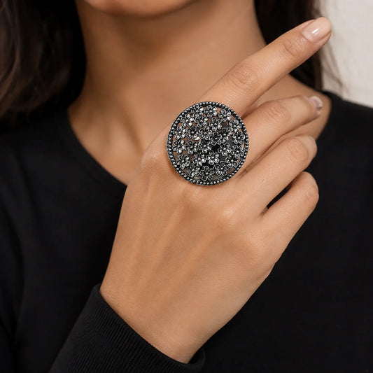 "Oxidised silver-tone statement
ring featuring an intricate oval openwork design with clustered floral detailing and an antique finish."