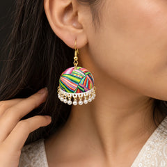"Pair of colourful jhumka
earrings with vibrant pink, green, yellow, blue, orange, and purple striped patterns, finished with delicate white bead danglers and gold-tone hooks."