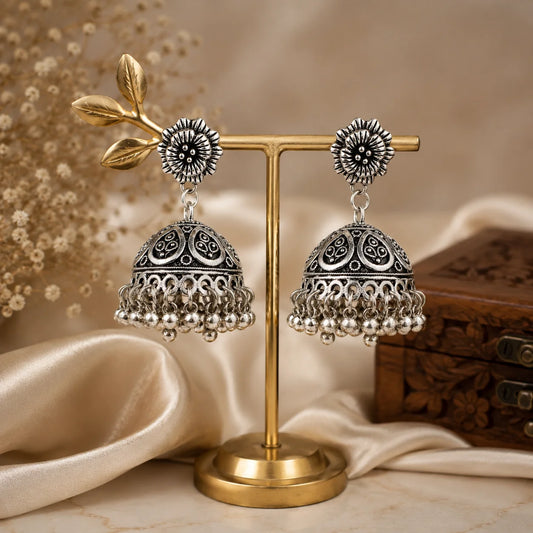 Oxidised silver dome jhumka earrings with ghungroo drops. Traditional bell-shaped earrings with leaf cutwork and floral top. Ethnic festive jewellery.