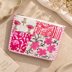 "Pink and white quilted
patchwork pouch featuring floral and botanical prints, a striped border, and a zip closure."