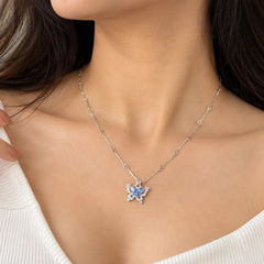 "Delicate silver-toned
necklace featuring a butterfly pendant with shimmering blue and iridescent stone accents, displayed on a dark background."