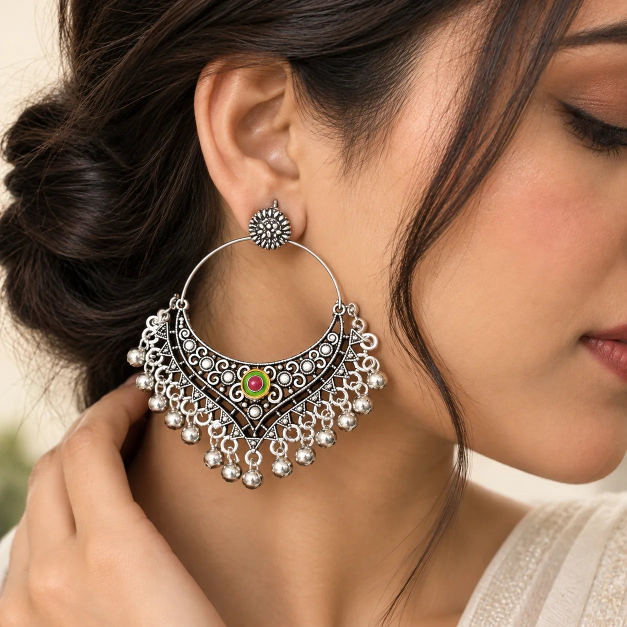 "Oxidised silver-tone
statement chandbali earrings featuring intricate filigree detailing, pink and green stone accents, and cascading silver bead embellishments."