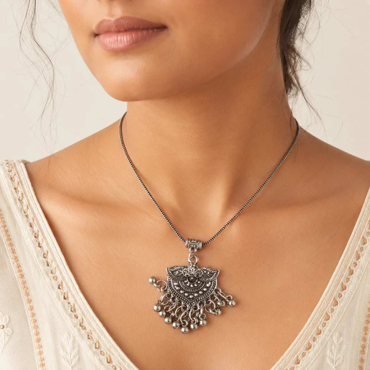 "Oxidised silver-tone necklace
 and earrings set featuring an intricate statement pendant with ghungroo-style danglers and matching ethnic stud earrings."
