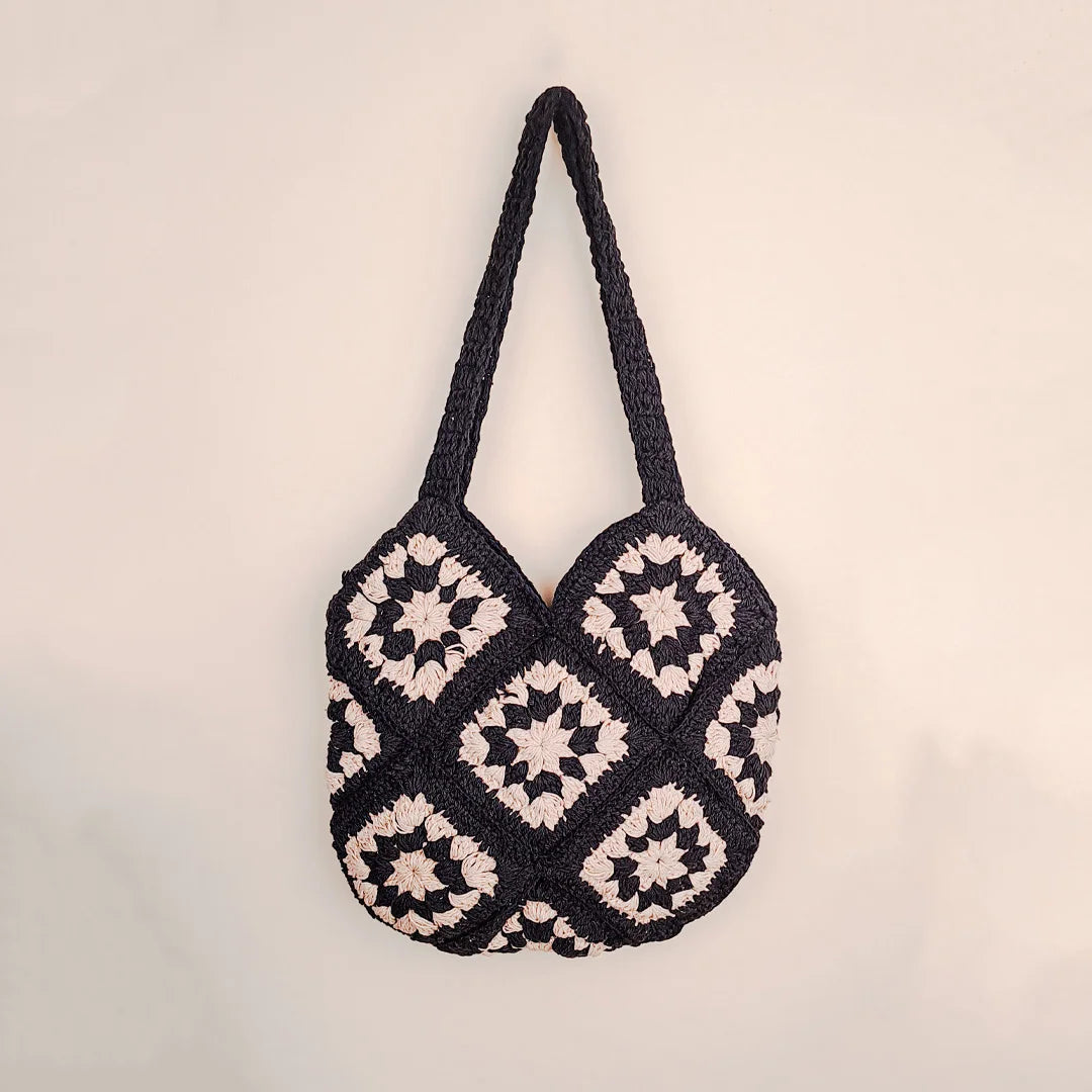 Handmade black and white crochet tote bag with granny square pattern, featuring long straps and a stylish monochrome design for everyday use.
