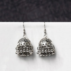 Oxidised jhumka earrings with intricate filigree dome detailing and ghungroo drops. Traditional bell-shaped design with rustic silver finish.

