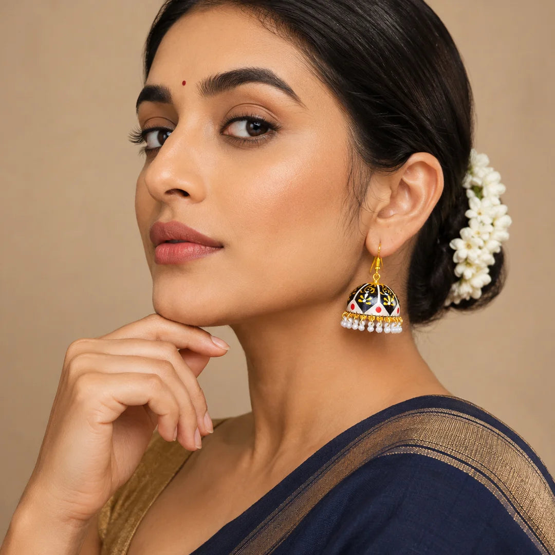 Black and gold dome jhumka earrings with intricate hand-painted motifs, subtle red accents, and pearl drop detailing, designed in a bold traditional style.
