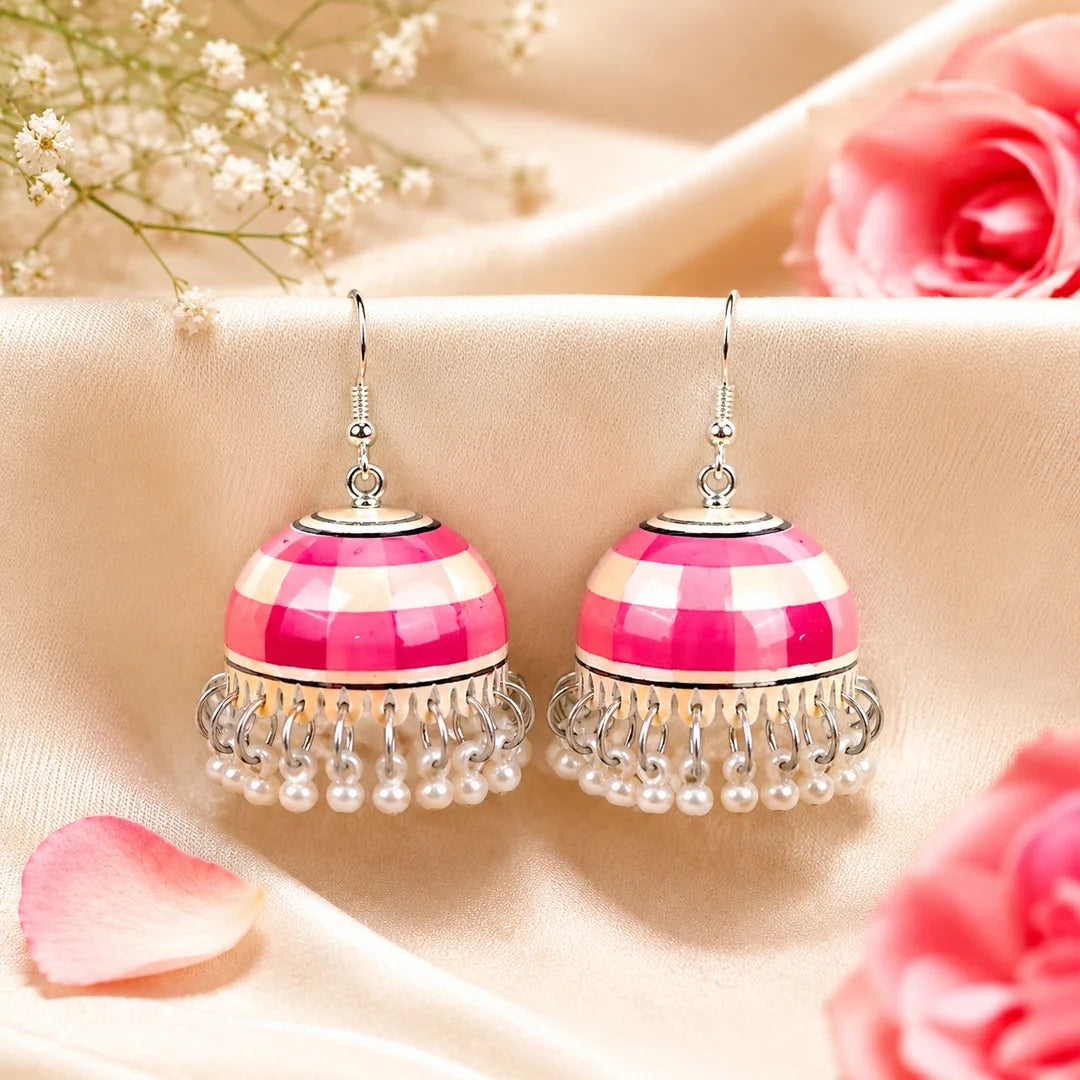 Pink and ivory striped dome-shaped jhumka earrings with silver detailing and small white pearl drops. Traditional earrings placed on a wooden surface with a handwritten tag.

