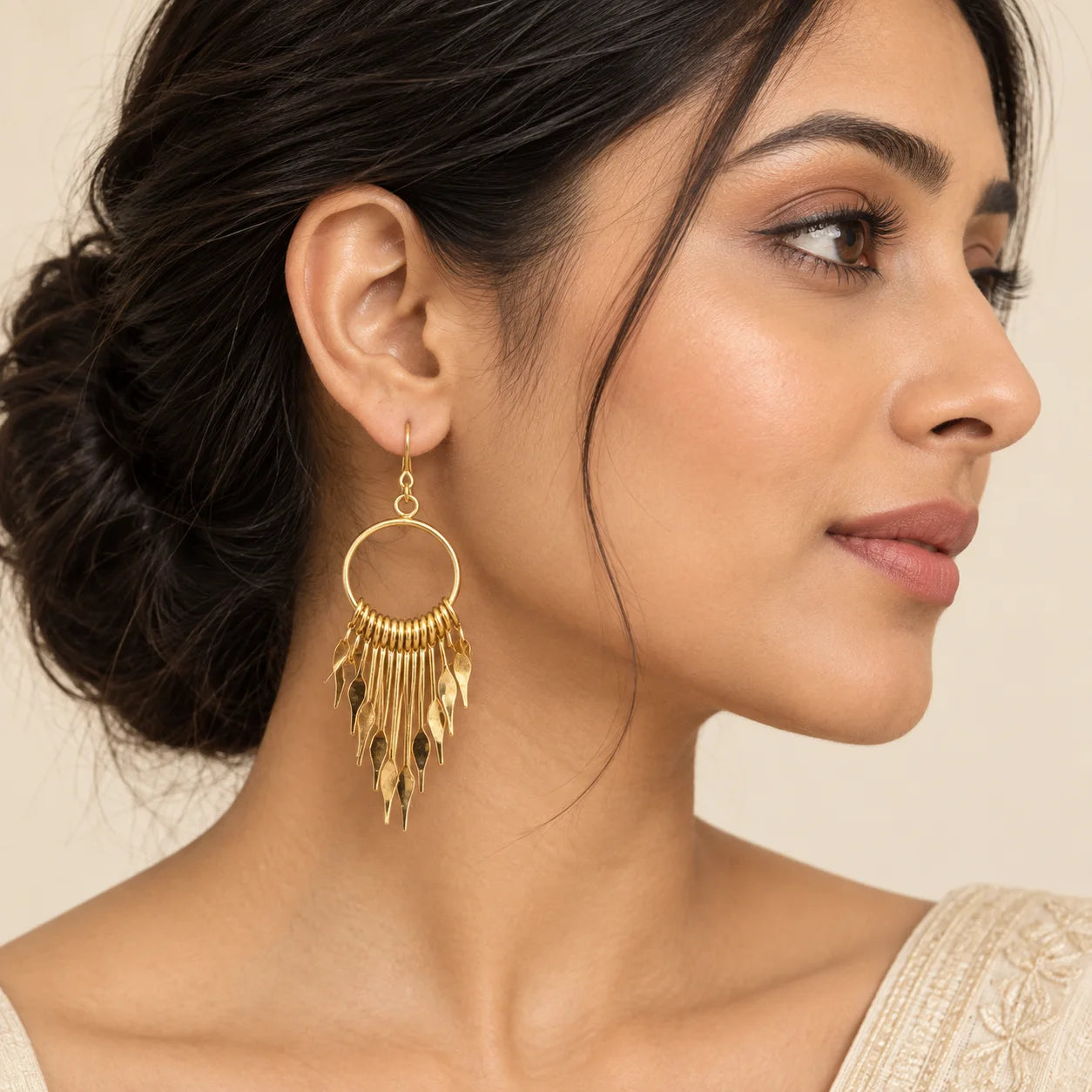 "Gold-tone dangle
 earrings featuring large circular hoops with layered cascading metal fringe and pointed geometric charms."
