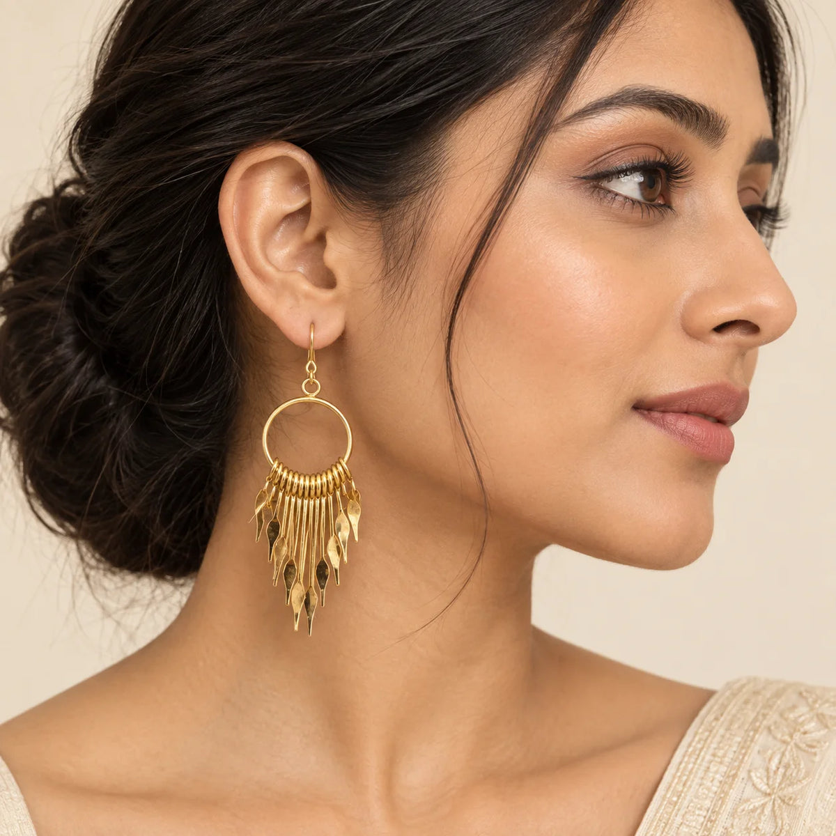 "Gold-tone dangle
 earrings featuring large circular hoops with layered cascading metal fringe and pointed geometric charms."
