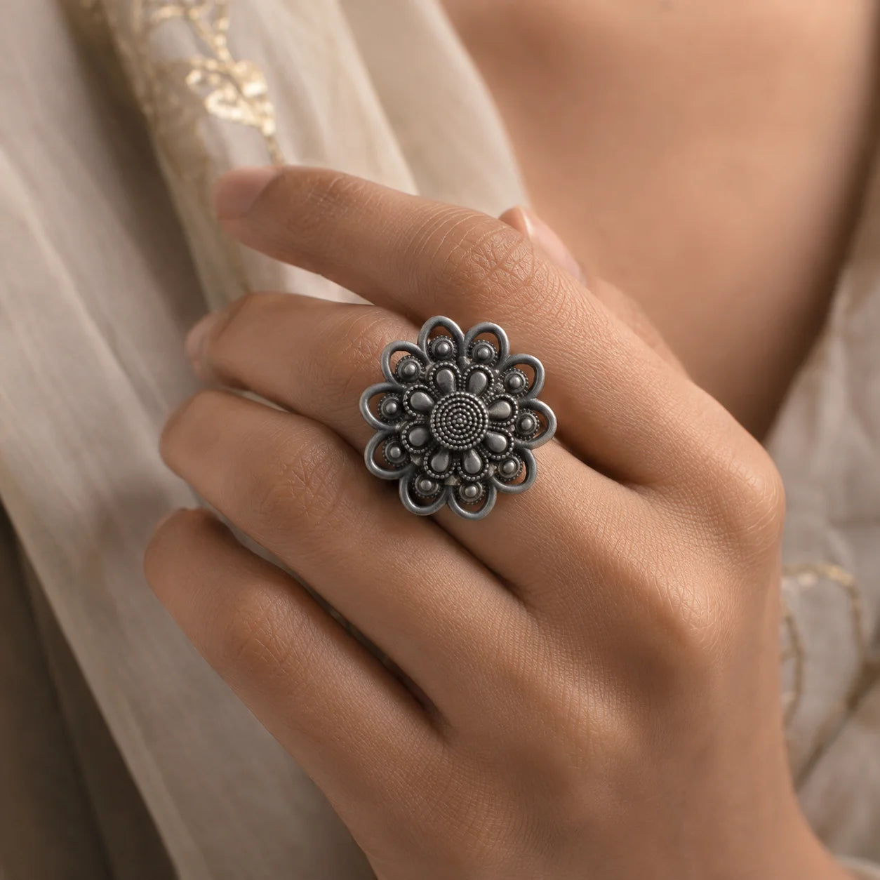 Black oxidised flower shaped statement ring with embossed petal design. Features beaded centers, spiral detail, and openwork outlines with matte antique finish. Adjustable boho ring for ethnic and daily wear.
