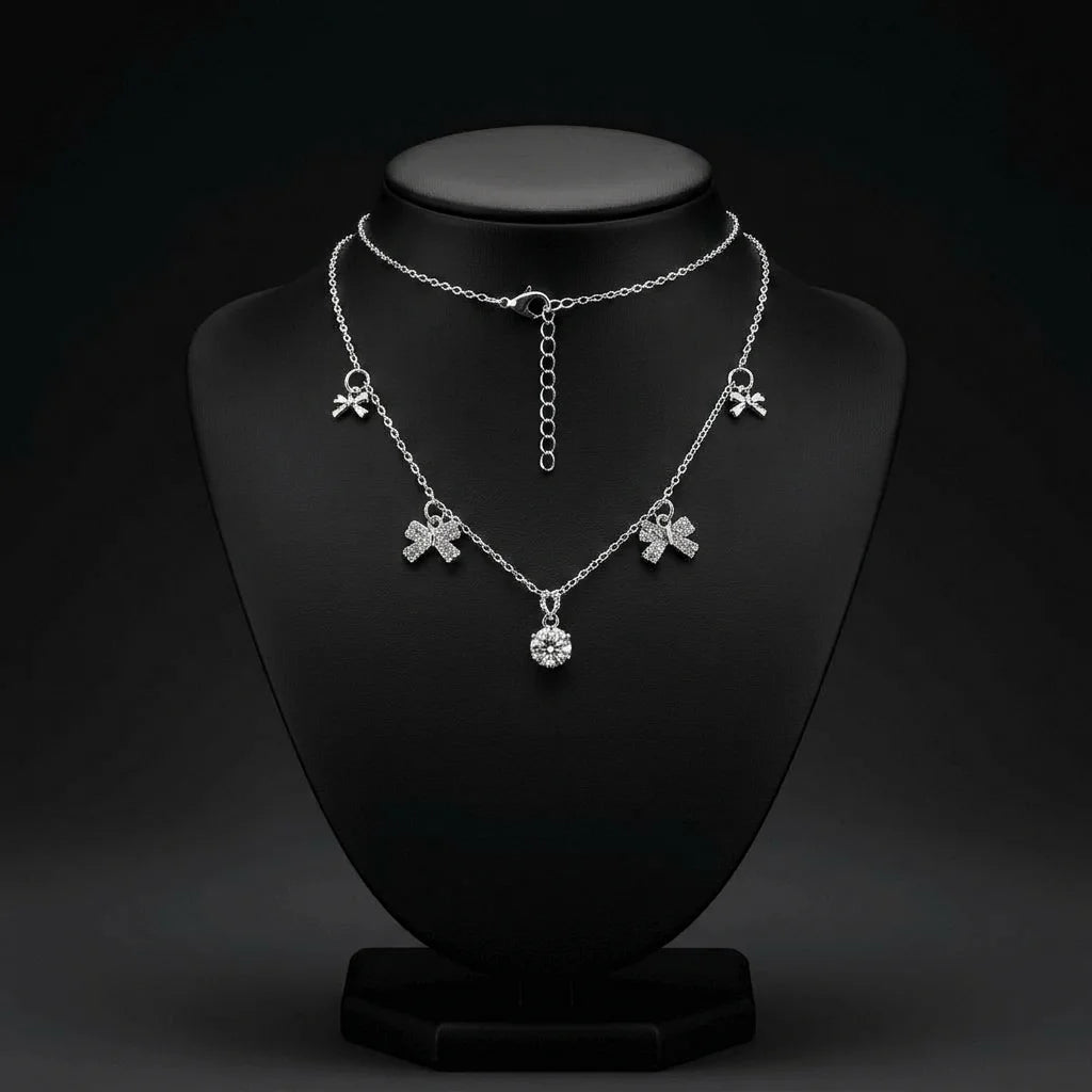 Bold silver tone necklace with large crystal bow charms and round crystal accent. Stainless steel with adjustable extender for fit. A statement demi-fine necklace for western, fusion, or party outfits.
