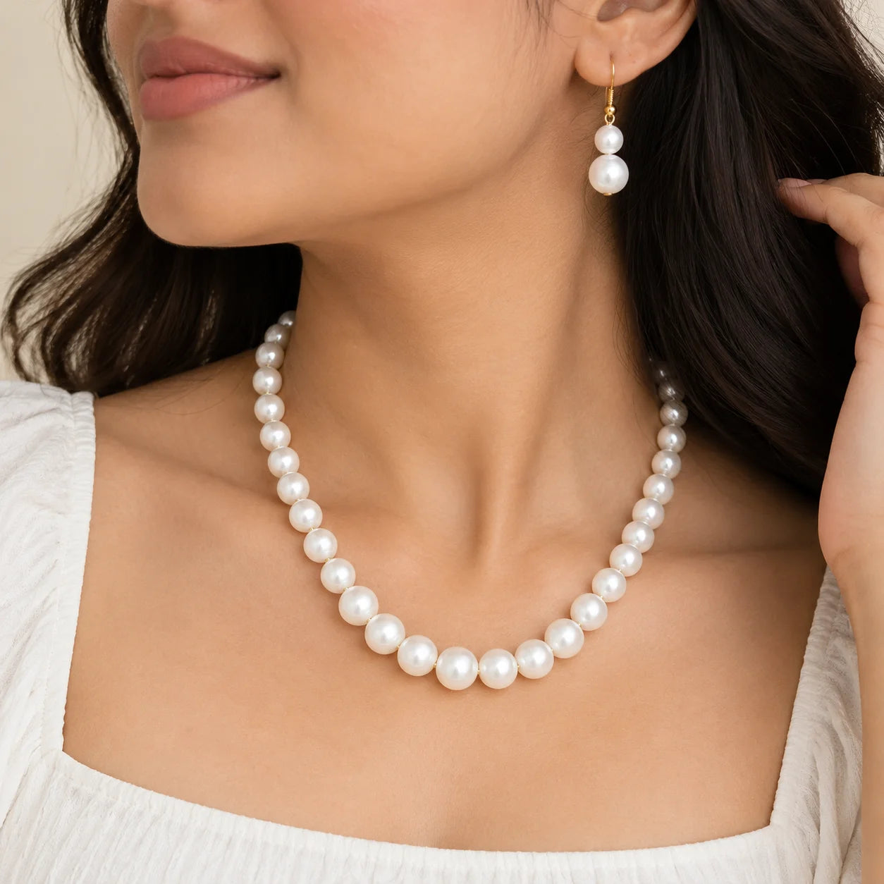 "White pearl necklace
 and matching drop earrings with graduated pearls and delicate gold-tone accents."
