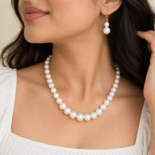"White pearl necklace
 and matching drop earrings with graduated pearls and delicate gold-tone accents."
