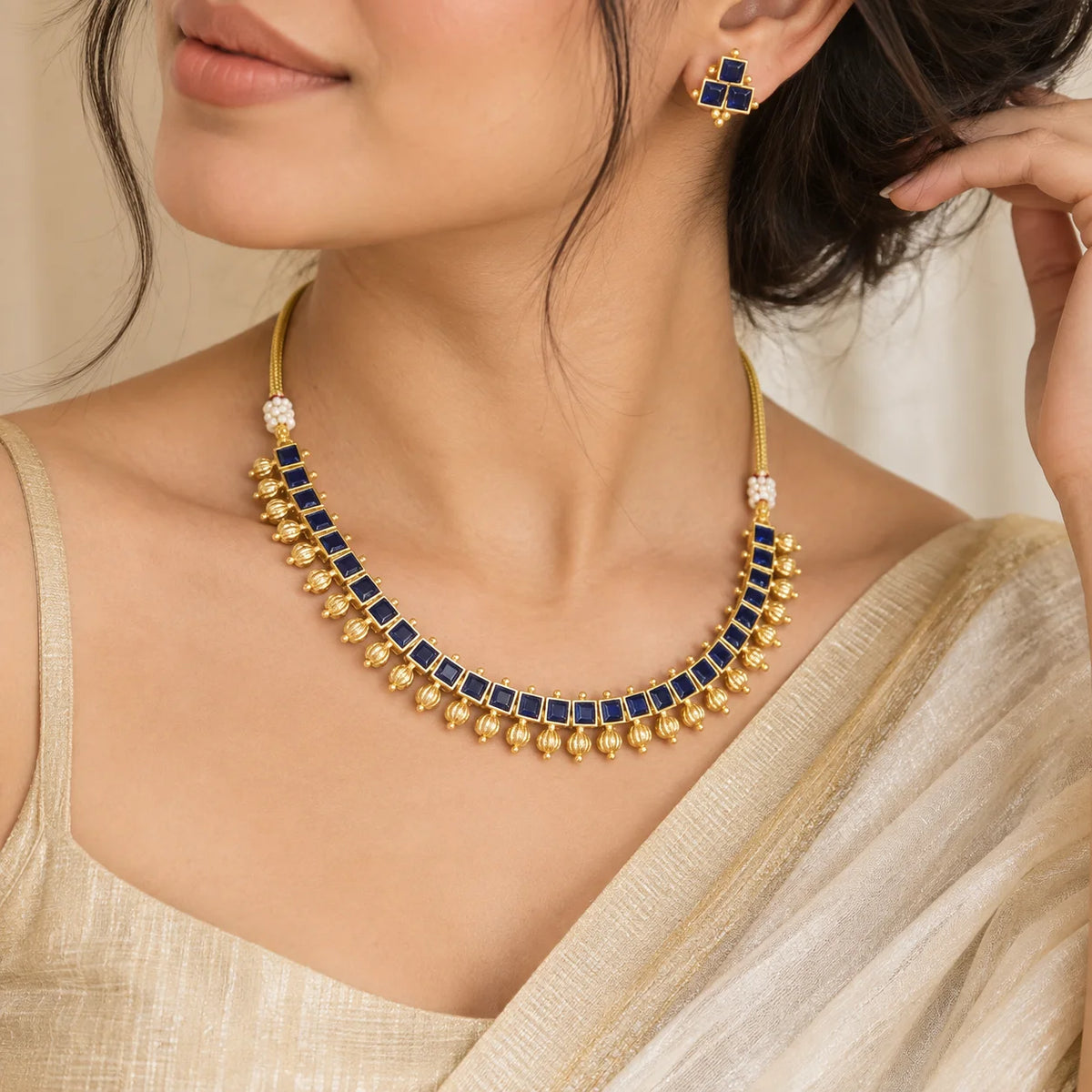 Blue kundan square necklace set with gold-toned detailing, dangling gold beads, and matching blue stone earrings.
