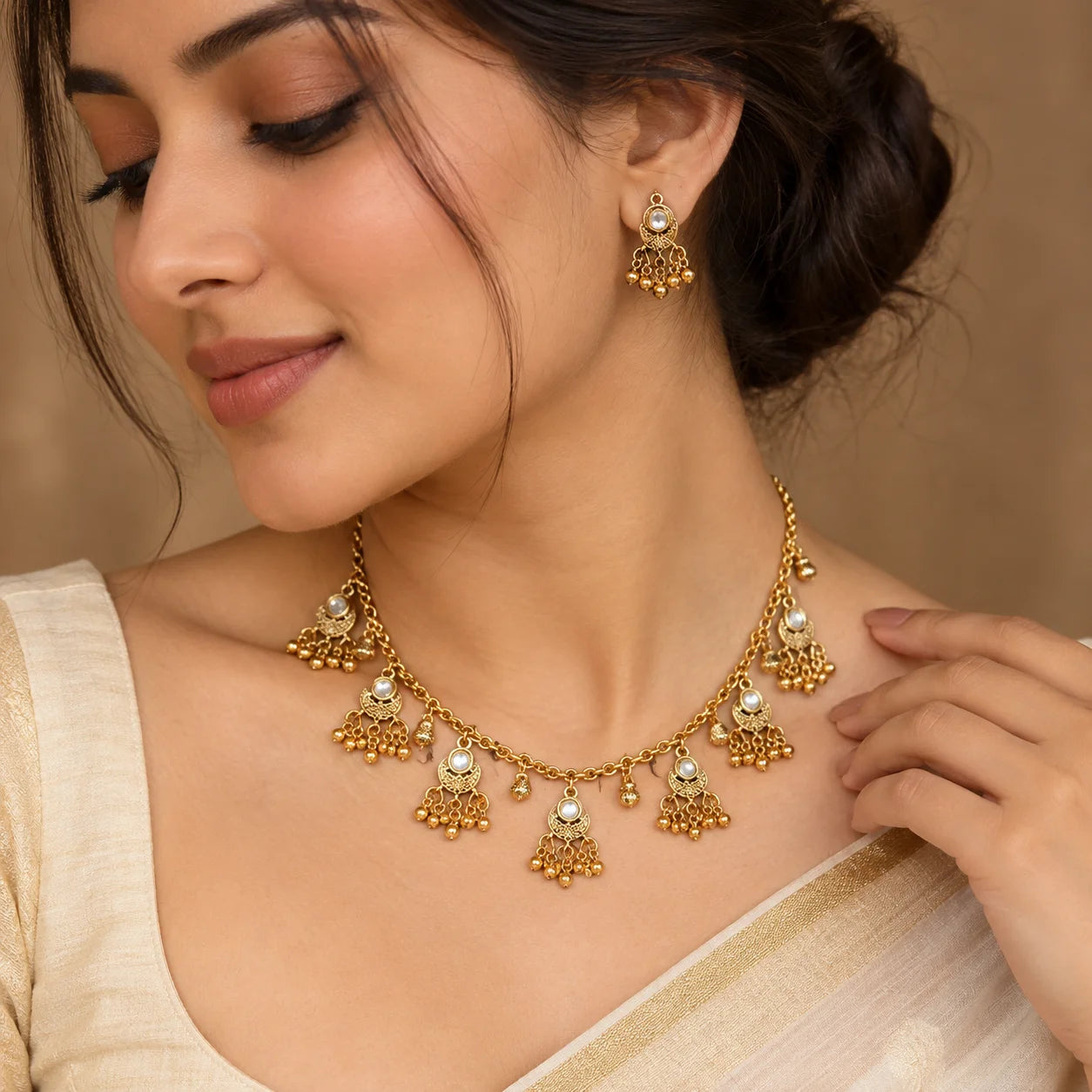 Gold chandbali necklace set with matching dangling earrings, featuring intricate traditional detailing, sparkling stones, and delicate hanging gold beads.
