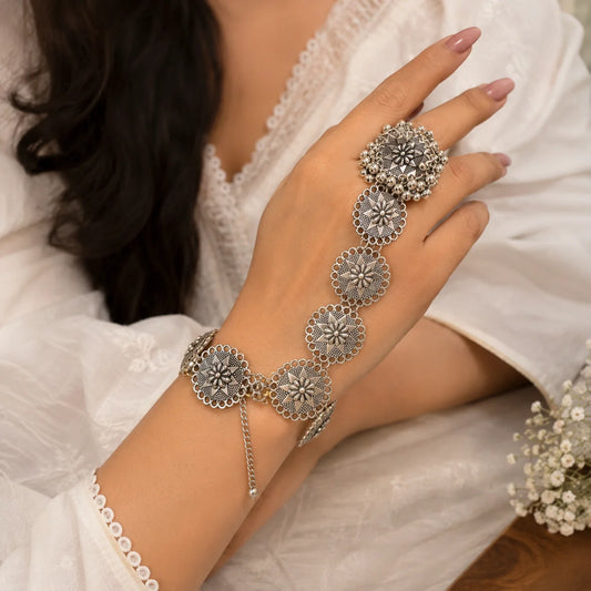 "Oxidised silver-tone 
hathphool for women featuring intricate floral medallions, traditional detailing, and ghungroo accents connected from finger to wrist."
