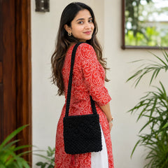 Black macramé bag with intricate geometric knot pattern, textured woven finish, and a long braided strap.

