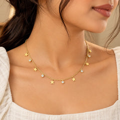 "Gold-toned dainty 
necklace featuring multiple star-shaped charms and small round accents arranged along a delicate chain."
