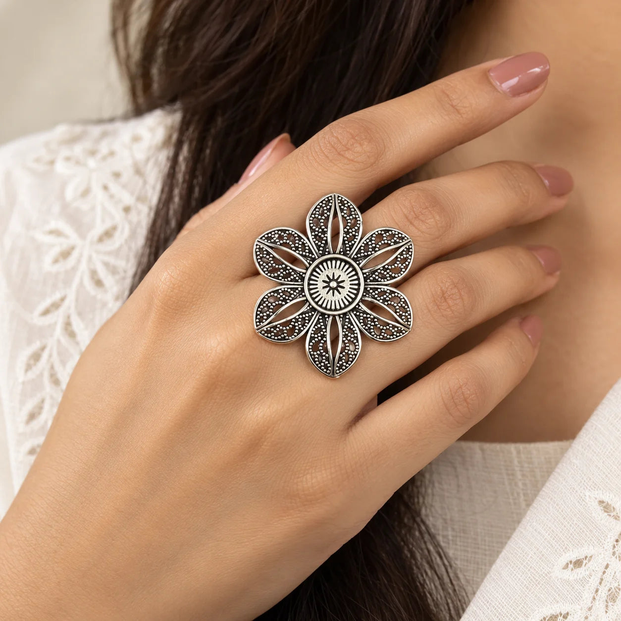 "Oxidised silver-tone 
statement ring featuring a large six-petal floral design with intricate dotted detailing and a patterned circular centre."
