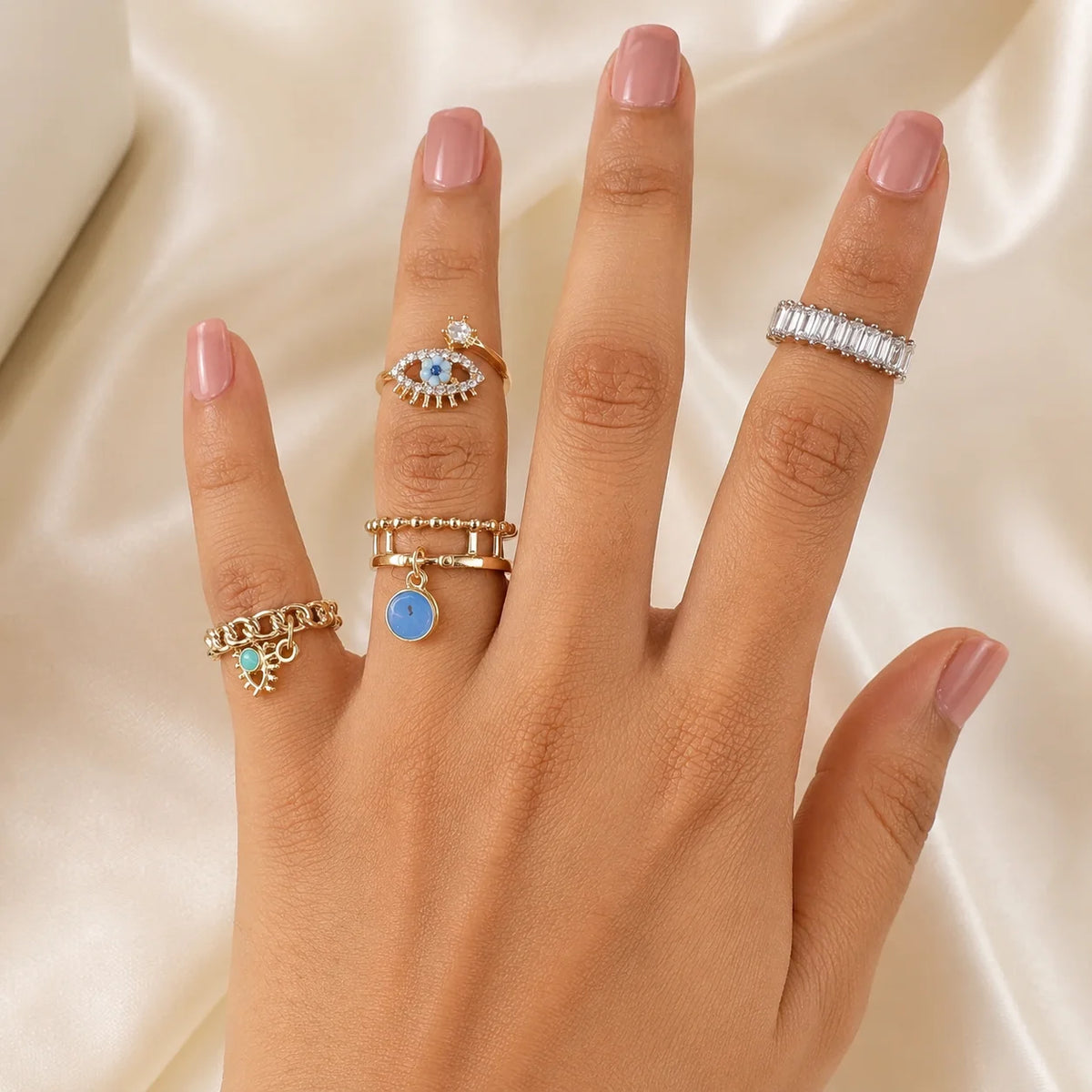 "4-piece gold-tone ring combo 
for women featuring sparkling crystal bands, evil eye motifs, blue enamel charm accents, and stackable statement rings. A stylish fashion ring set perfect for everyday wear, layering, gifting, and contemporary jewellery styling."
