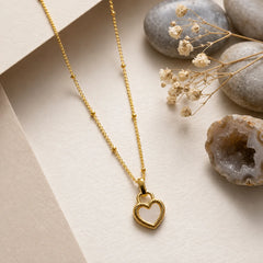 "Gold heart pendant necklace 
featuring a white heart charm in a textured gold-tone frame, suspended from a delicate chain. A minimalist and elegant necklace for women, perfect for everyday wear, layering, gifting, and special occasions."
