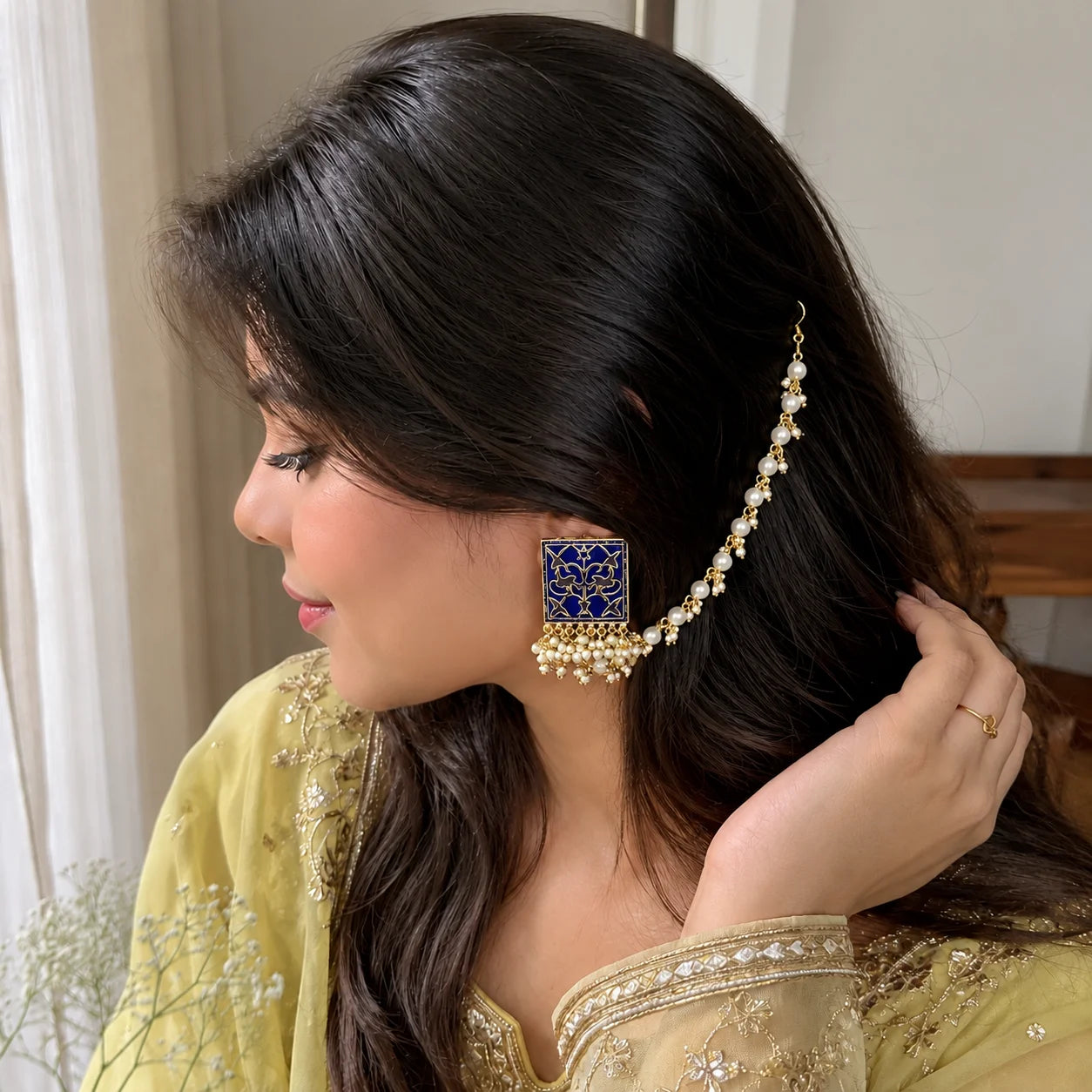 "Navy blue Meenakari statement 
earring with intricate gold detailing, square-shaped enamel design, and delicate pearl-like ear chain."
