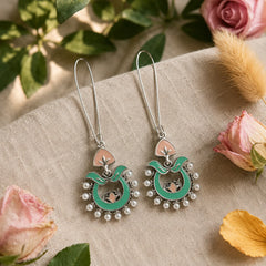 These traditional enamel hoop earrings feature hand-painted turquoise enamel work, delicate pink lotus detailing, and a halo of pearl beads on an silver chandbali frame. The wire hook design keeps them lightweight for all-day wear, while the vibrant enamel adds a festive pop to ethnic and indo-western outfits. Each piece reflects classic Indian craftsmanship with a modern boho twist.
