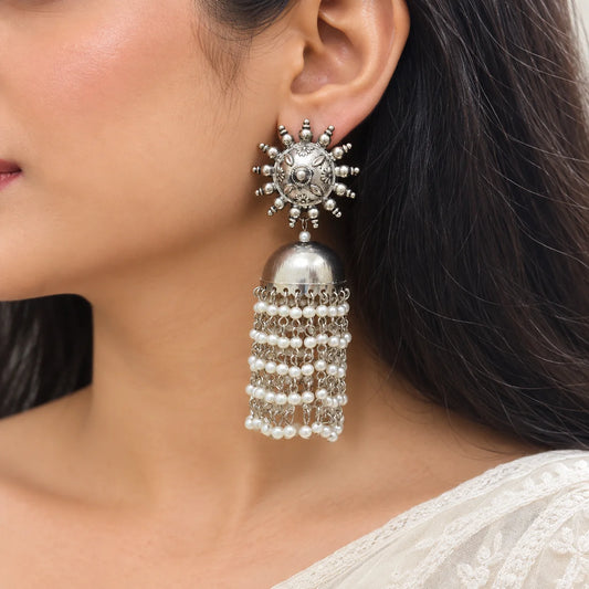 "Oxidised silver-tone statement
 jhumka earrings with engraved floral stud design, dome-shaped detailing, and cascading pearl tassels. Traditional ethnic earrings for women, ideal for weddings, festive occasions, Navratri, Diwali, Haldi, Mehendi, and pairing with sarees, lehengas, kurtas, and Indo-western outfits."
