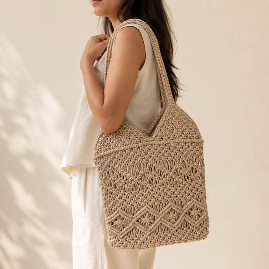 "Beige macramé tote bag 
featuring intricate knotted patterns, woven detailing and comfortable shoulder straps for a boho everyday look."
