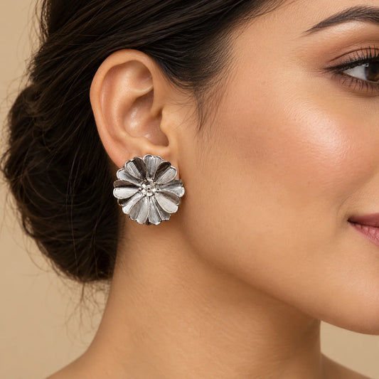 "Pair of silver-tone floral
 stud earrings featuring layered petals with fine textured detailing and a polished finish."
