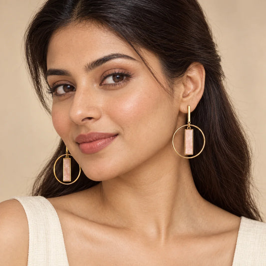 "Gold-tone geometric
 earrings featuring large circular hoops with rectangular pink stone accents in the center."
