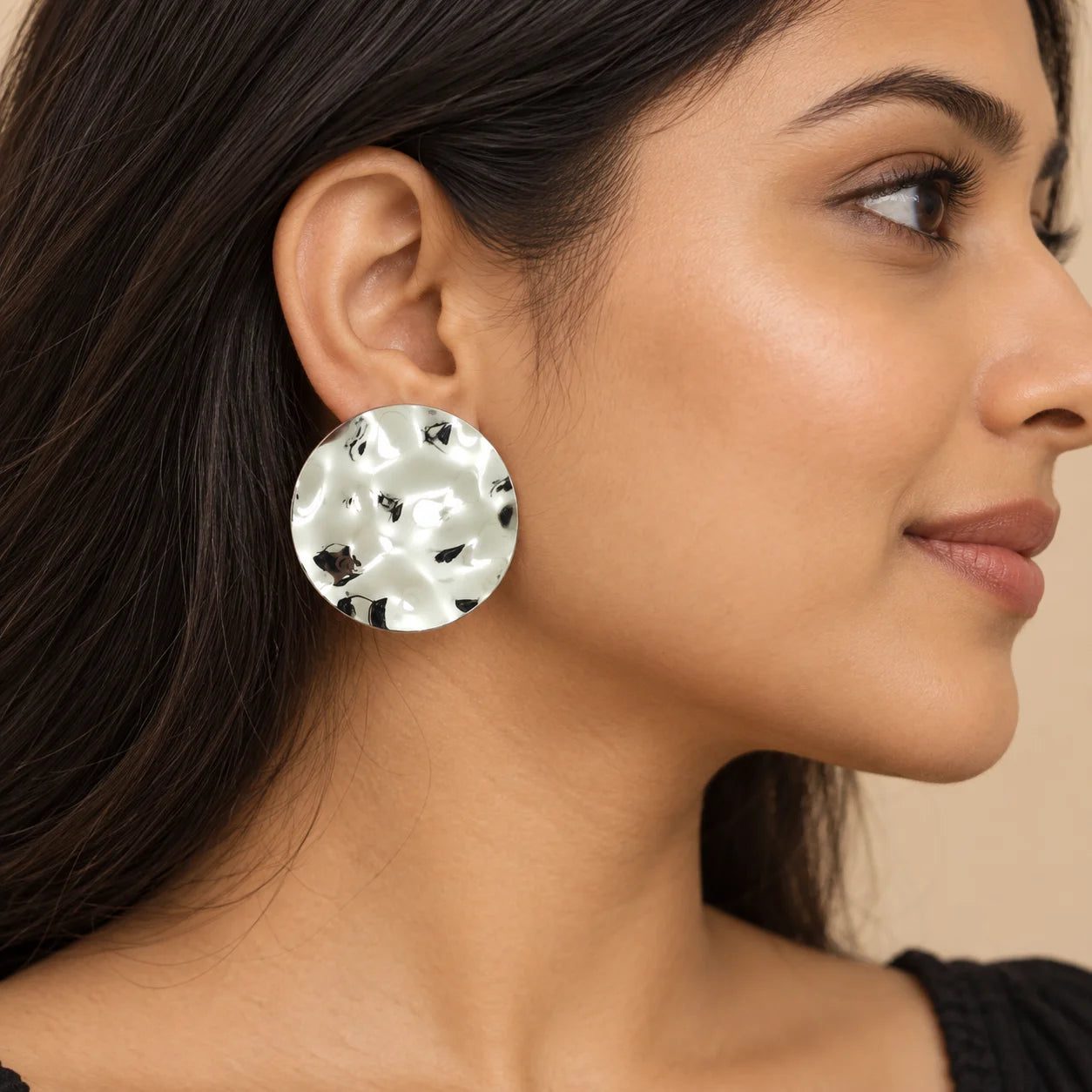 "Pair of oversized silver-tone
 statement earrings featuring round, organically textured discs with a reflective, hammered-style finish."
