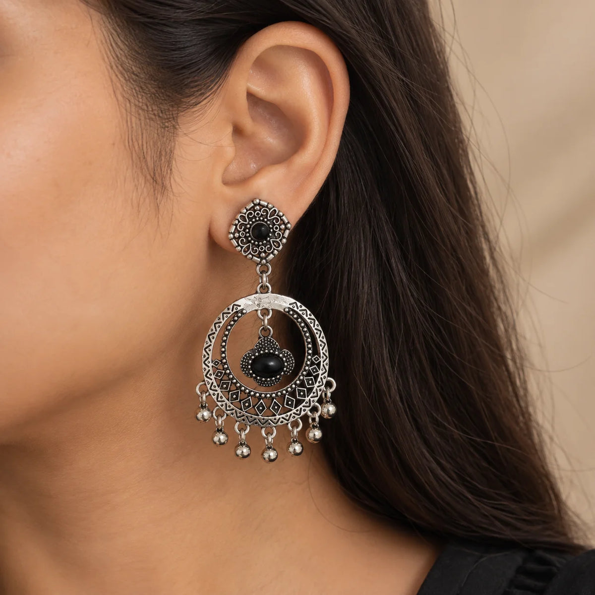 "Pair of oxidised silver-tone
 earrings featuring intricate floral and geometric patterns, large circular drops, central hanging charms, and tiny silver bead accents."
