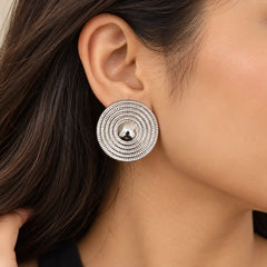 "Pair of silver-tone 
statement earrings featuring concentric textured circular rings with smooth polished centres."
